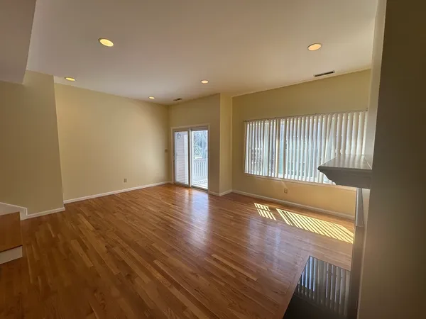 a view of an empty room with wooden floor and a window