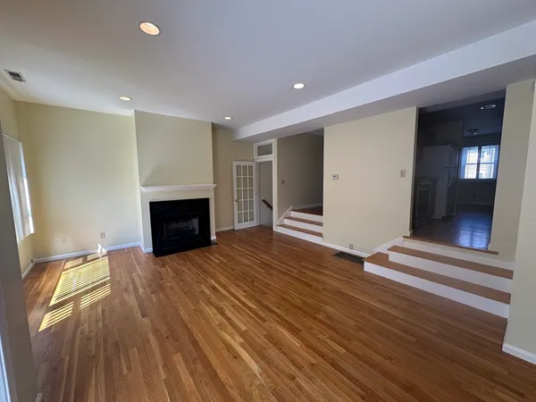 a view of an empty room with wooden floor fireplace and a window