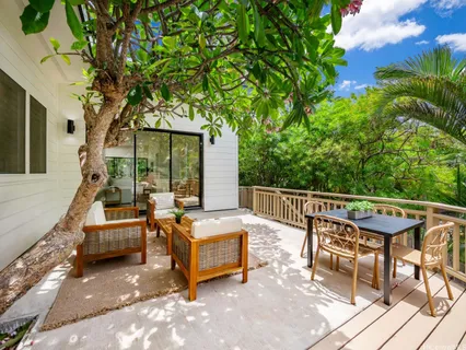a view of a patio with a table and chairs under an umbrella with large trees