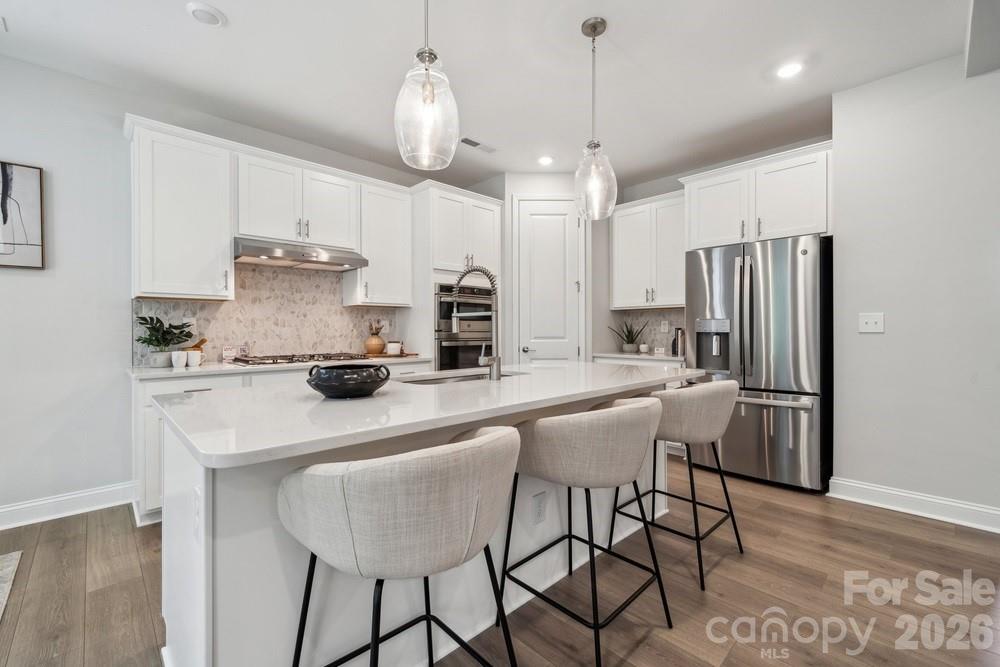 a kitchen with stainless steel appliances a table chairs refrigerator and microwave