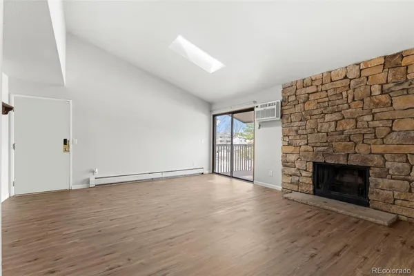 an empty room with wooden floor fireplace and windows