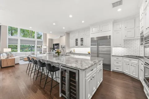 a kitchen with stainless steel appliances granite countertop lots of white cabinets and wooden floor