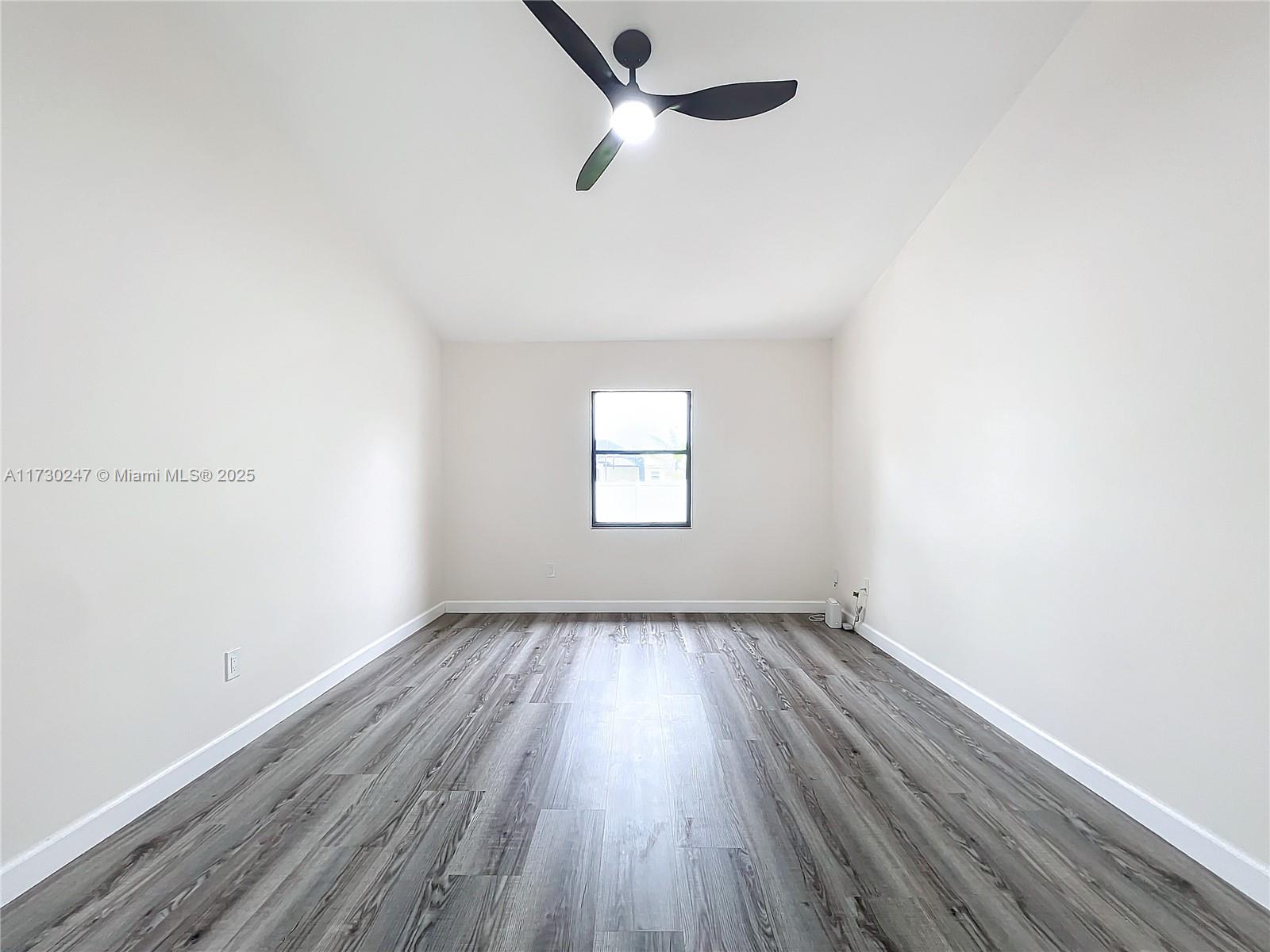 521 Southwest Rabbit Avenue Port St. Lucie, FL 34953 - Photo 31 of 45 an empty room with wooden floor ceiling fan and window
