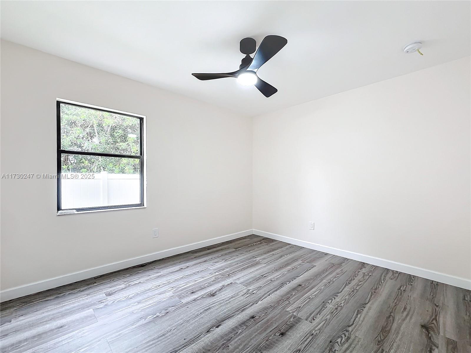 521 Southwest Rabbit Avenue Port St. Lucie, FL 34953 - Photo 40 of 45 a view of a room with wooden floor a ceiling fan and windows