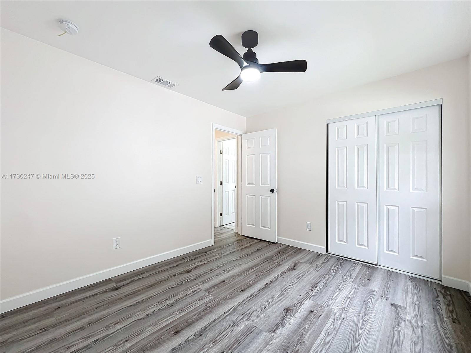 521 Southwest Rabbit Avenue Port St. Lucie, FL 34953 - Photo 42 of 45 an empty room with wooden floor ceiling fan and window