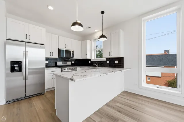 a kitchen with stainless steel appliances granite countertop a refrigerator a stove a microwave and a hard wood floors