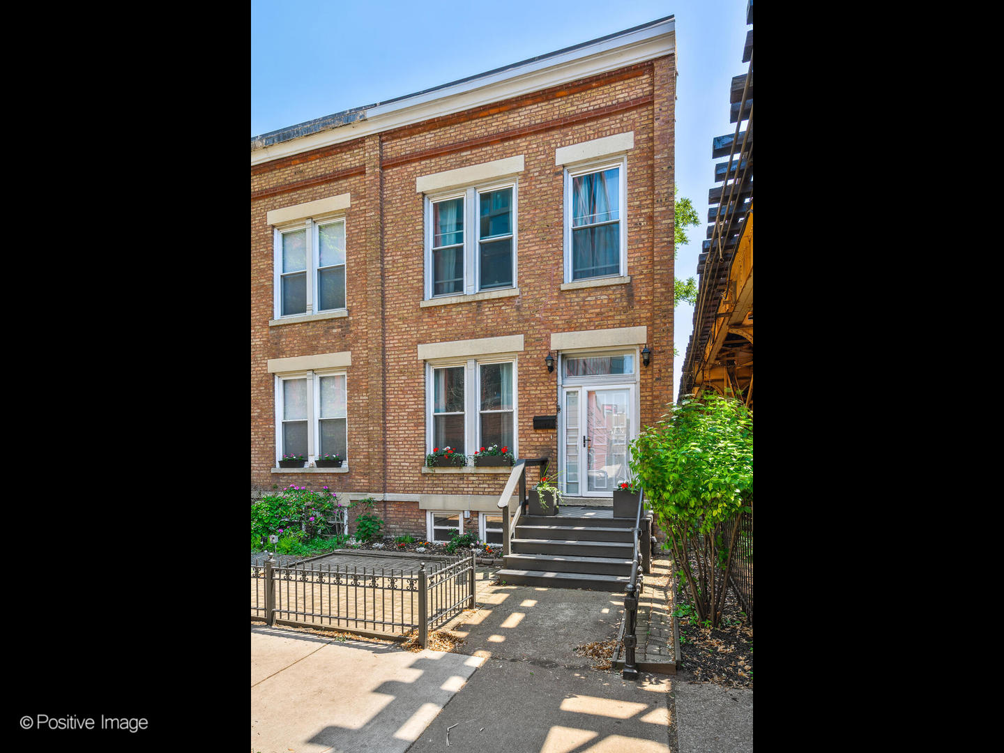 a view of a brick house with many windows and plants