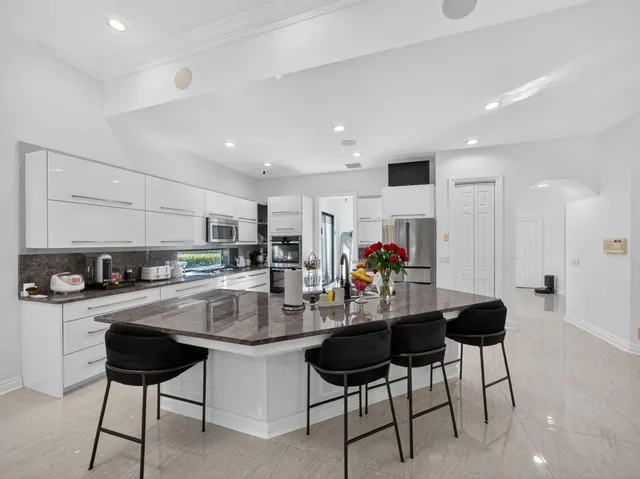 a kitchen with stainless steel appliances kitchen island granite countertop a refrigerator and a stove top oven with wooden floor