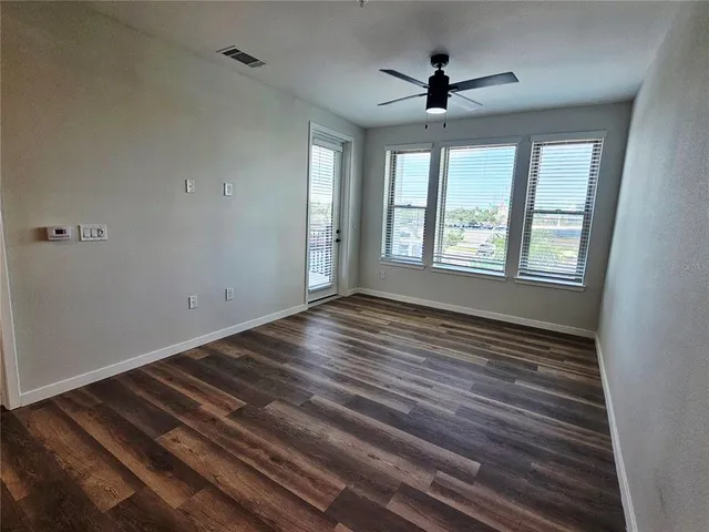 a view of empty room with wooden floor and fan