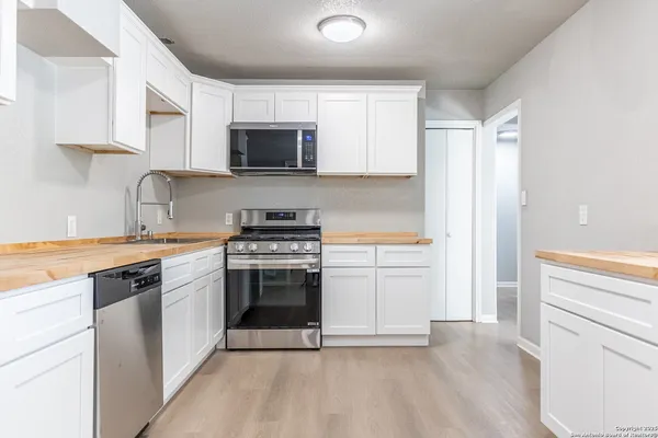 a kitchen with stainless steel appliances white cabinets and a stove top oven
