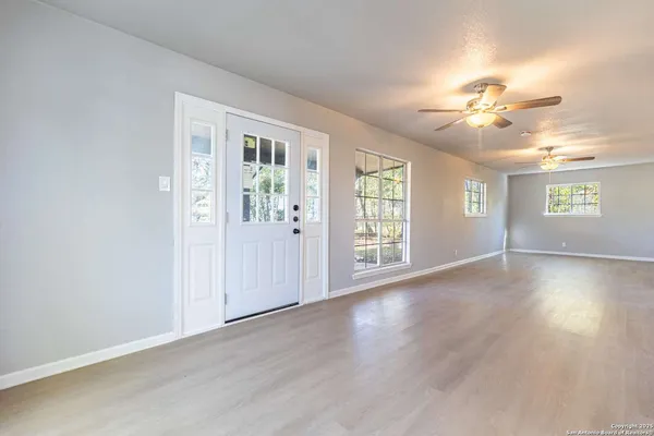 a view of an empty room with window and wooden floor