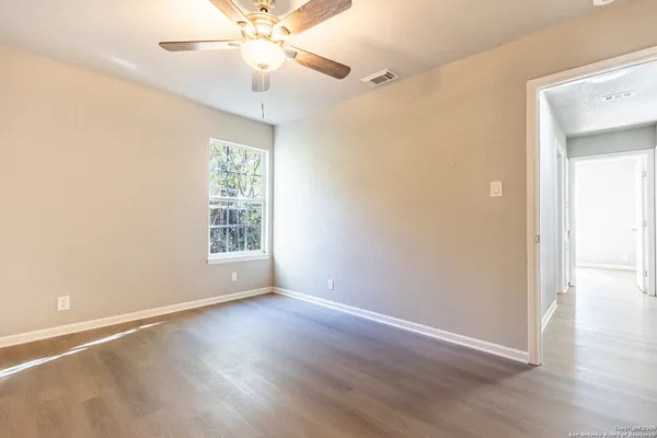 a view of an empty room with wooden floor and a window