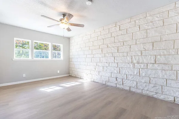 an empty room with windows and fan