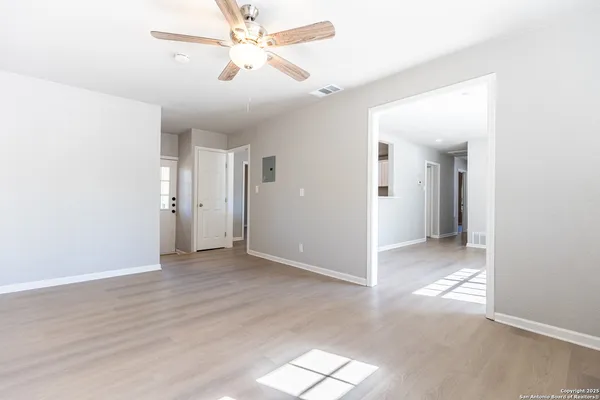 a view of an empty room and window with a fan