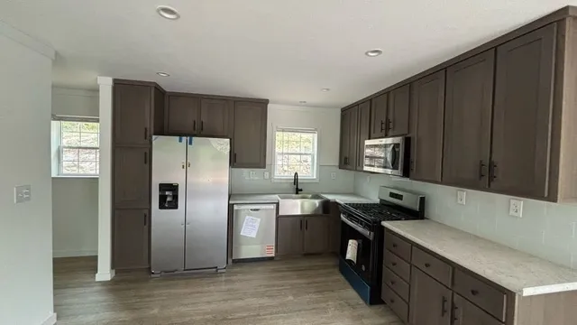 a kitchen with stainless steel appliances wooden cabinets a sink and a refrigerator