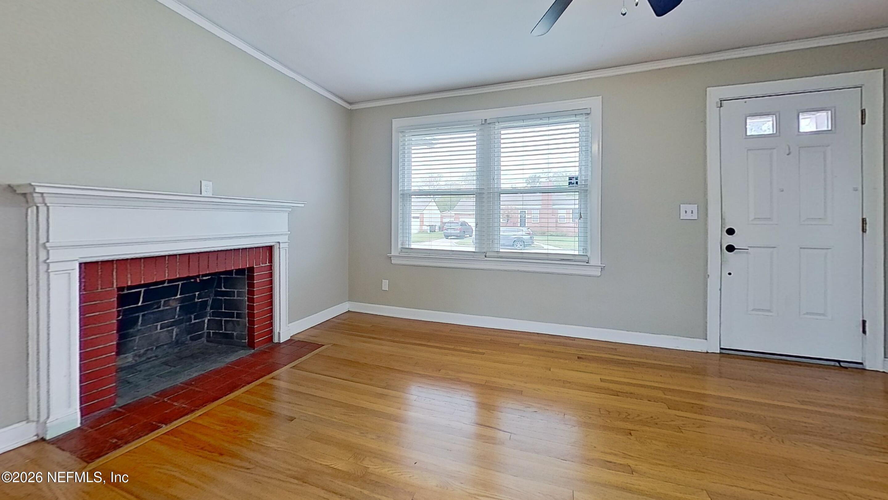 2151 Traymore Road Jacksonville, FL 32207 - Photo 5 of 18 a view of an empty room with wooden floor fireplace and a window