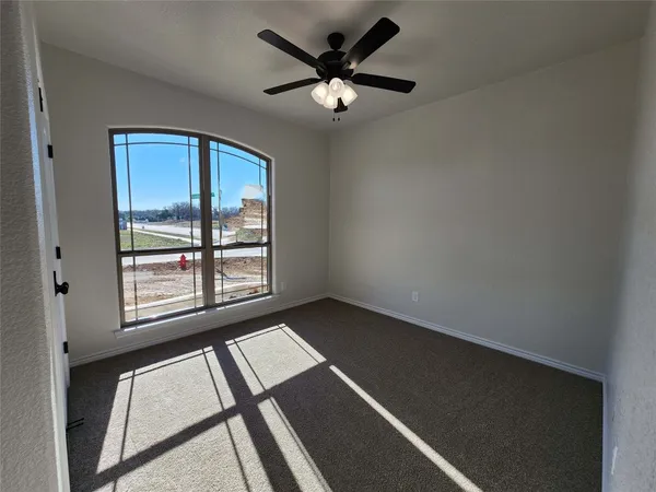an empty room with windows and ceiling fan