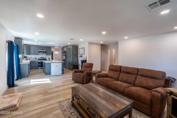 a living room with furniture kitchen view and a wooden floor