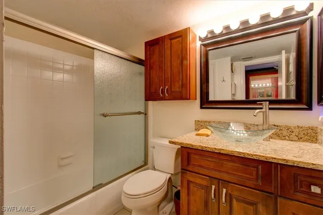 a bathroom with a granite countertop toilet sink and mirror
