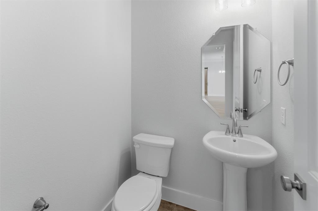 2316 Quartz Street Krum, TX 76249 - Photo 12 of 29 Pedestal sink with chrome faucet, octagonal mirror, and wall-mounted light fixture