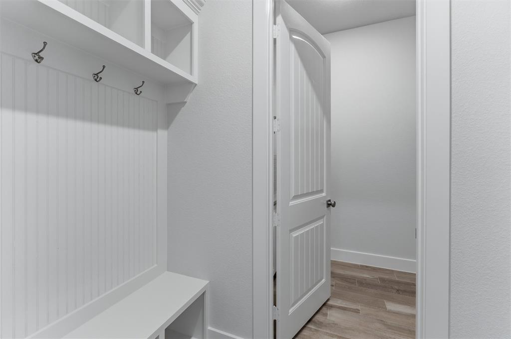 2316 Quartz Street Krum, TX 76249 - Photo 17 of 29 Built-in white storage unit featuring a bench, shelving, beadboard backing, and metal hooks