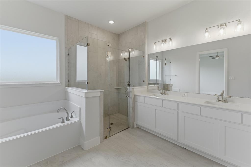2316 Quartz Street Krum, TX 76249 - Photo 21 of 29 Bathroom featuring a freestanding tub, glass-enclosed shower, dual vanity with undermount sinks, and wall-mounted light fixtures