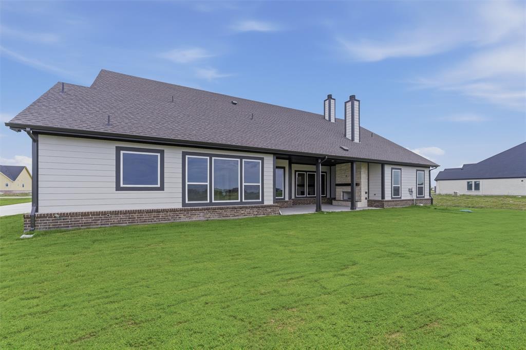 2316 Quartz Street Krum, TX 76249 - Photo 27 of 29 Expansive rear exterior featuring a covered patio, multiple large windows, and a dual-flue chimney system