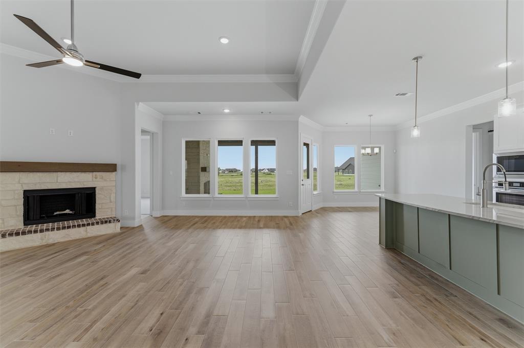 2316 Quartz Street Krum, TX 76249 - Photo 6 of 29 Open-concept living space featuring wood-finish flooring, a stone fireplace with a wood mantle, and a contemporary ceiling fan