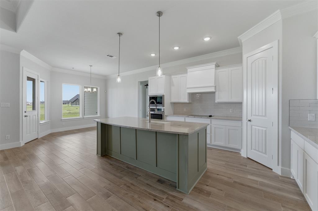 2316 Quartz Street Krum, TX 76249 - Photo 8 of 29 Expansive kitchen and dining area featuring a prominent island with pendant lighting, wood-finish flooring, white cabinetry, and recessed lighting