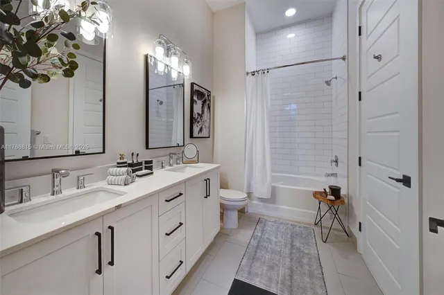 a spacious bathroom with a double vanity sink a toilet a mirror and shower