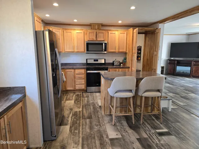 a kitchen with stainless steel appliances granite countertop a stove top oven a sink dishwasher a dining table and chairs with wooden floor