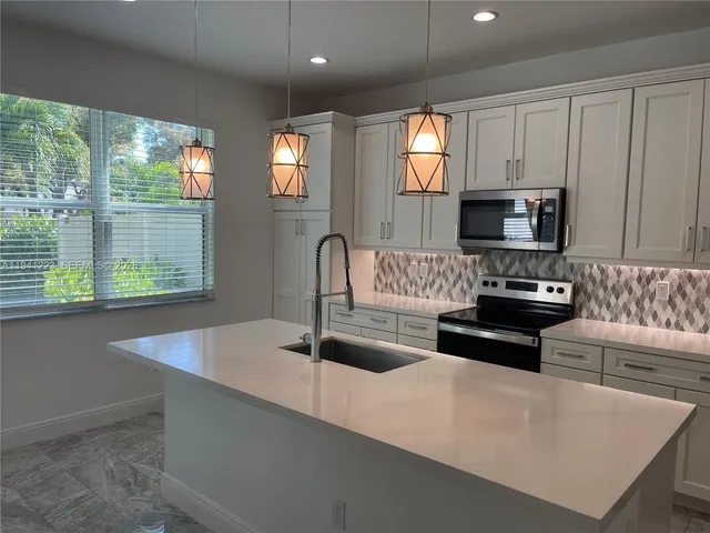 a kitchen with granite countertop a stove and a white refrigerator