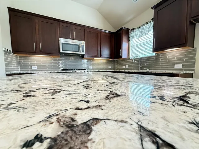a kitchen with granite countertop wooden cabinets a sink and a stove