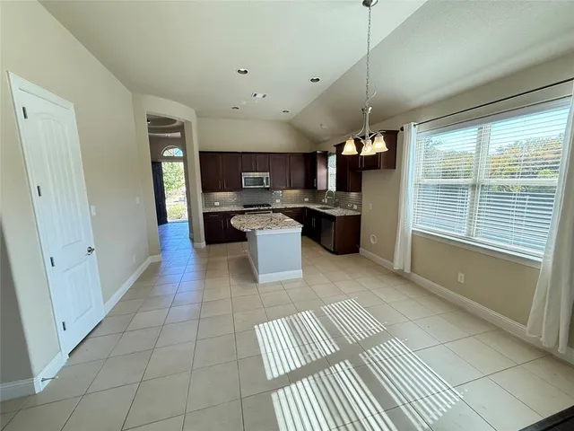 a kitchen with stainless steel appliances kitchen island granite countertop a refrigerator and a sink