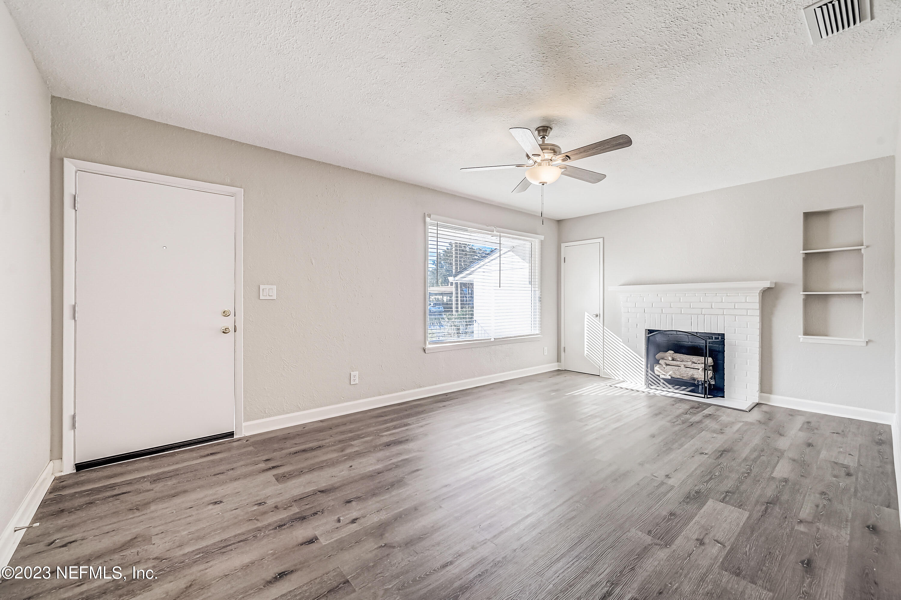 6105 Duke Road Jacksonville, FL 32217 - Photo 5 of 29 an empty room with windows a fireplace and a chandelier fan