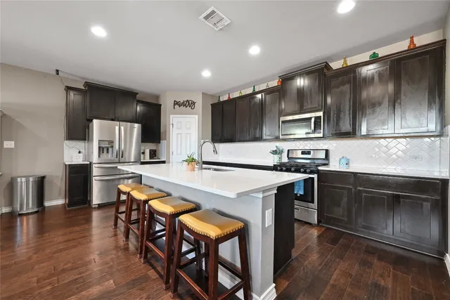 a kitchen with stainless steel appliances kitchen island granite countertop a stove a sink a microwave and a refrigerator