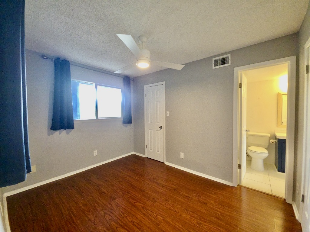 2500 Burleson Road, Unit 521 Austin, TX 78741 - Photo 18 of 20 Bedroom featuring wood-finish flooring, a ceiling fan with integrated lighting, and a window with curtain rods
