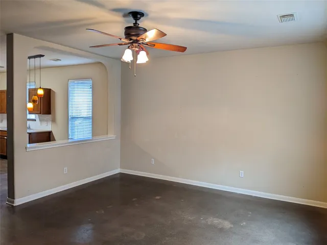 an empty room with a window and a chandelier fan