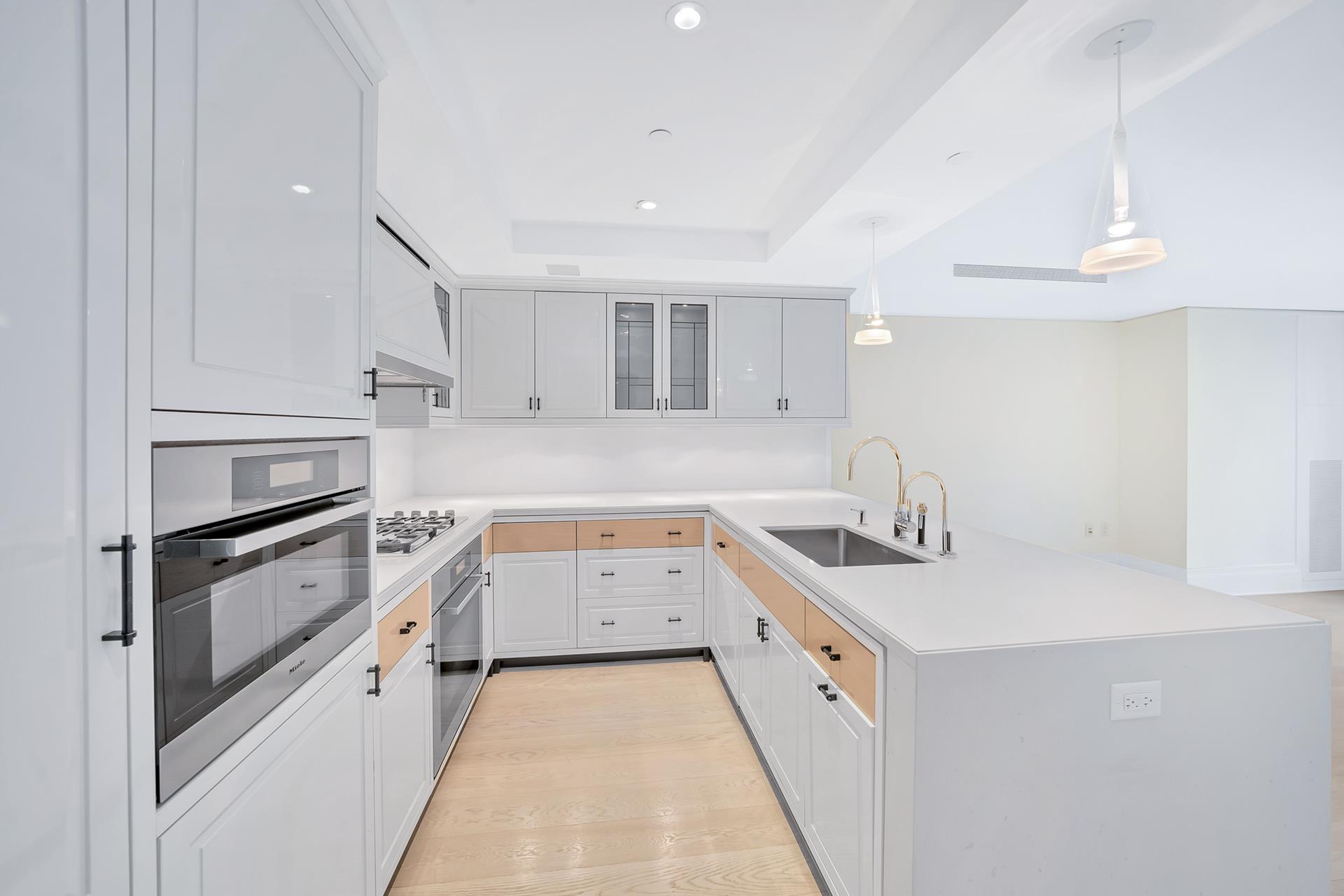 21 East 61st Street, Unit 9D Manhattan, NY 10065 - Photo 3 of 14 a kitchen with granite countertop white cabinets and white appliances