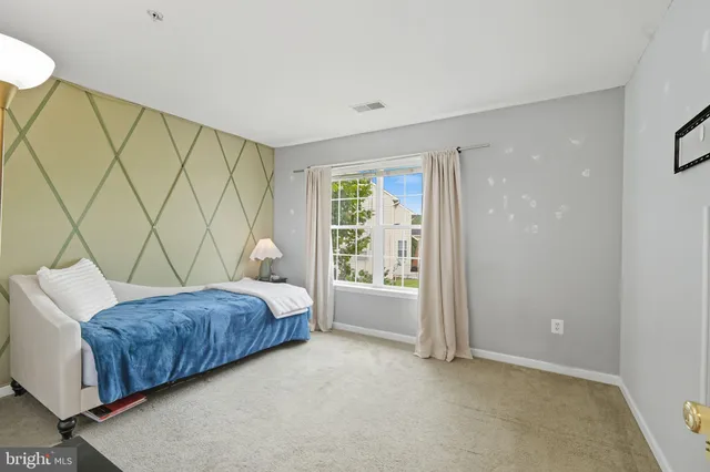 a bedroom with a bed and a chair with the bookshelf