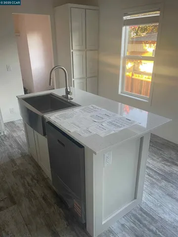 a close view of a sink a faucet cabinets and a wooden floor