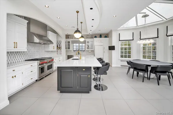 a kitchen with stainless steel appliances kitchen island granite countertop a table chairs sink and cabinets