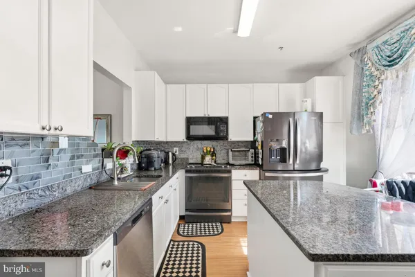 a kitchen with stainless steel appliances granite countertop a sink stove microwave and refrigerator