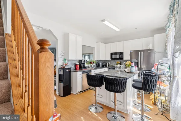 a kitchen with stainless steel appliances kitchen island granite countertop dining table chairs and a refrigerator