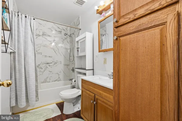 a bathroom with a granite countertop bathtub shower sink vanity and toilet