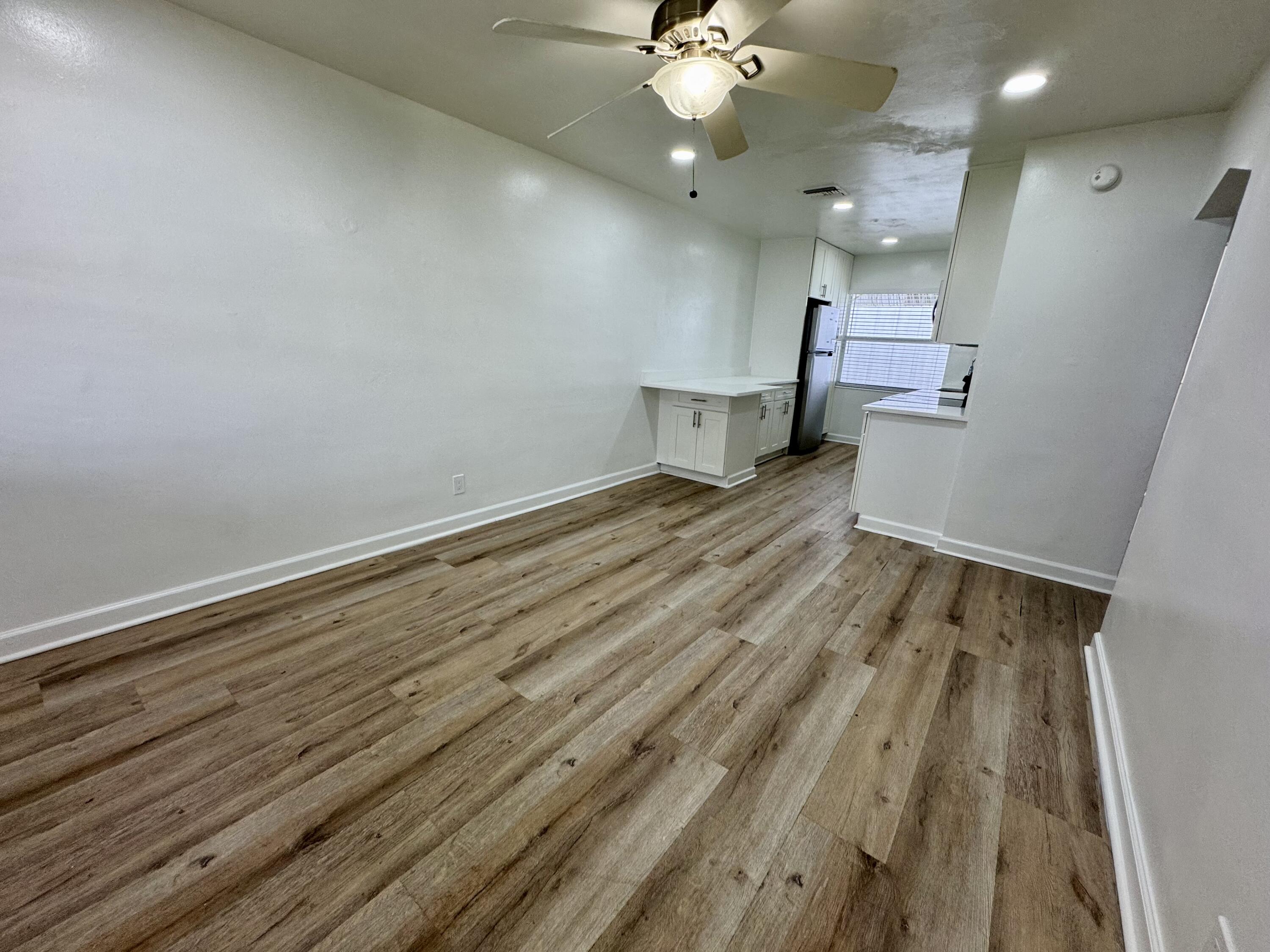 1235 Beach Road, Unit 2 Singer Island, FL 33404 - Photo 7 of 12 an empty room with wooden floor a ceiling fan and kitchen view