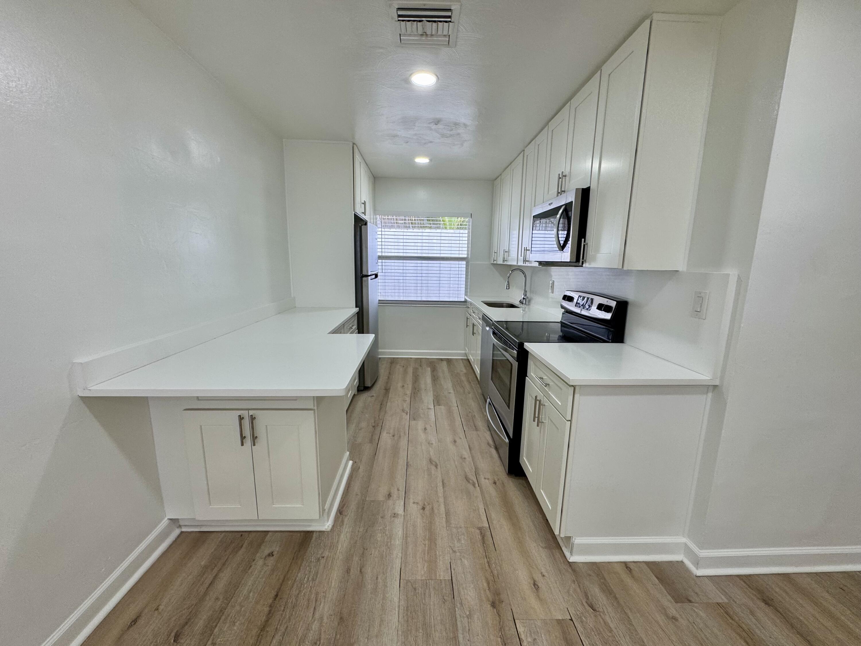 1235 Beach Road, Unit 2 Singer Island, FL 33404 - Photo 8 of 12 a kitchen with cabinets a sink and wooden floor