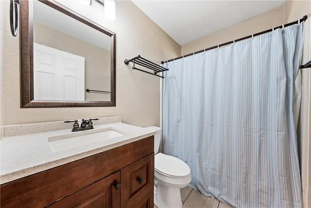a bathroom with a sink a toilet a mirror and shower curtain