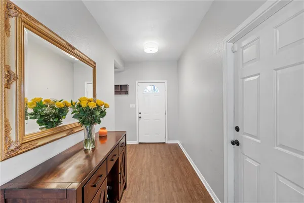 a view of a hallway to a livingroom with wooden floor and a potted plant