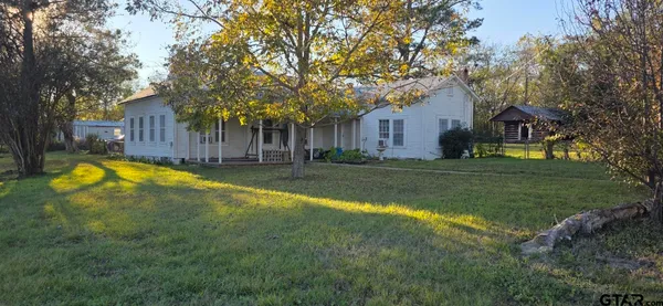 a view of a house with a big yard and large trees